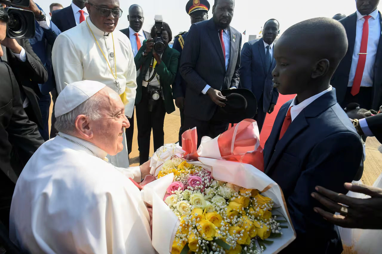 El papa Francisco recibe un ramo de flores de un niño cuando llega al Aeropuerto Internacional de Juba, en Sudán del Sur, el 3 de febrero de 2023