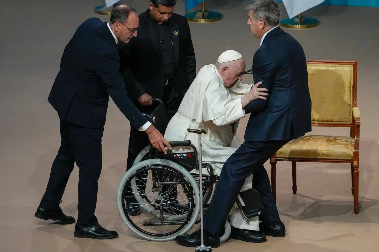 Ayudan al papa Francisco a ponerse de pie cuando llega a una reunión con autoridades, la sociedad civil y diplomáticos en la Sala de Conciertos Qazaq en Nur-Sultan, Kazajstán, el 13 de septiembre d